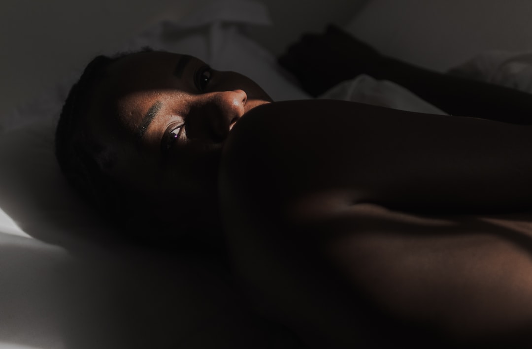 An African woman is lying on a bed as light falls on her face