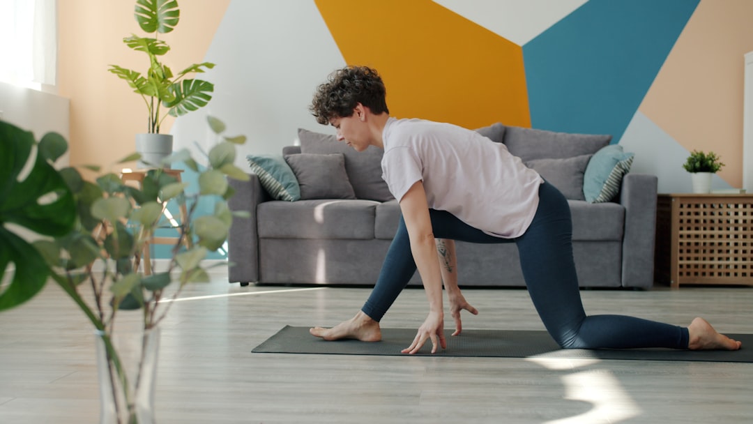A flexible young woman is doing yoga alone at home, practicing asanas on a comfortable mat and enjoying a beneficial activity. Indoor sports, active lifestyle, and modern youth concept.