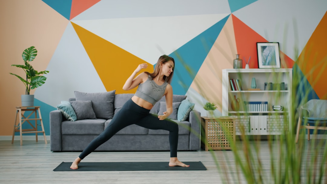 A beautiful girl is doing yoga exercises on the floor at home, stretching her body and focusing on the practice. Youth, indoor, and healthy lifestyle concept.